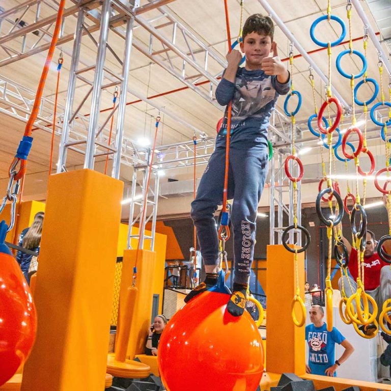 Niño superando un obstáculo colgante con cuerdas en Ninja Planet de Urban Planet, demostrando fuerza y equilibrio.